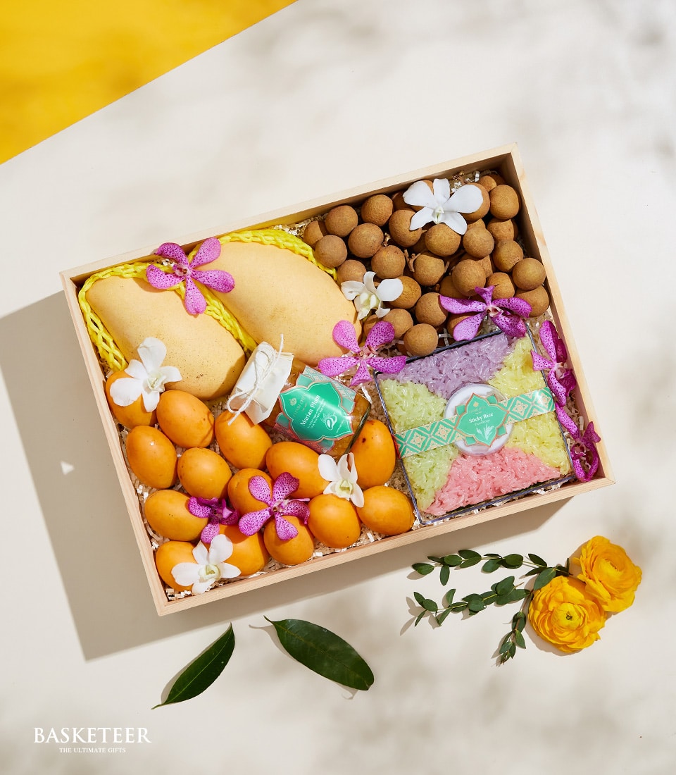 Premium Thai fruit gift box with mangoes, longans, marian plums, orchids, and sticky rice condiments