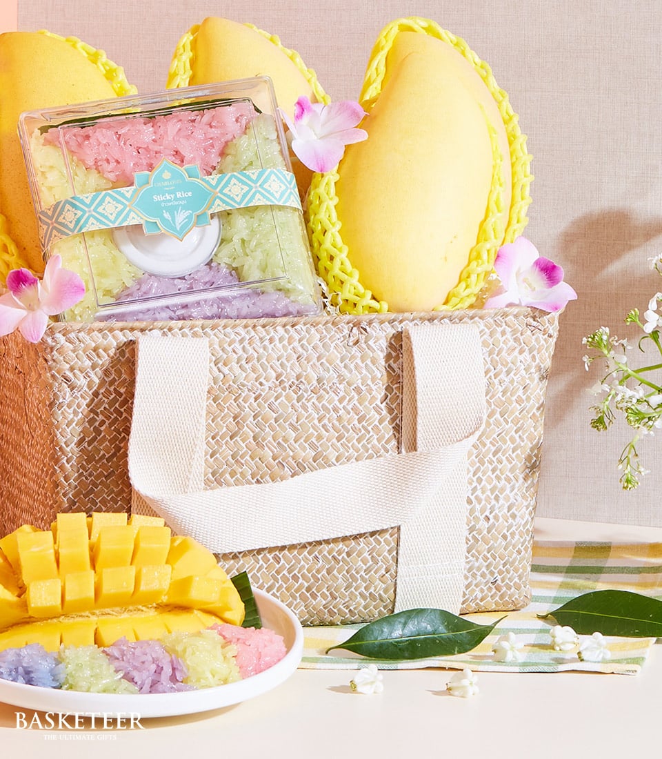 Mango and sticky rice gift basket with three ripe yellow mangoes and multi-colored sticky rice in woven straw