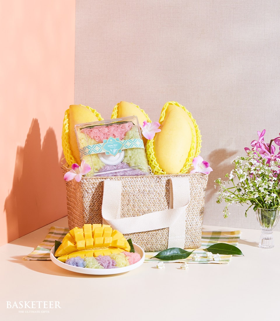 Yellow mangoes and sticky rice gift set in woven basket with coconut milk and banana leaf presentation