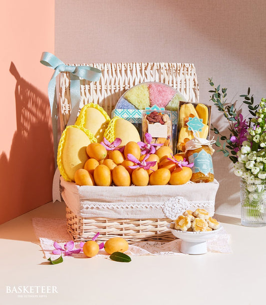 Wicker gift basket with Thai mangoes, tropical fruits, purple orchids, dried mango, nuts, and jam preserve with light blue