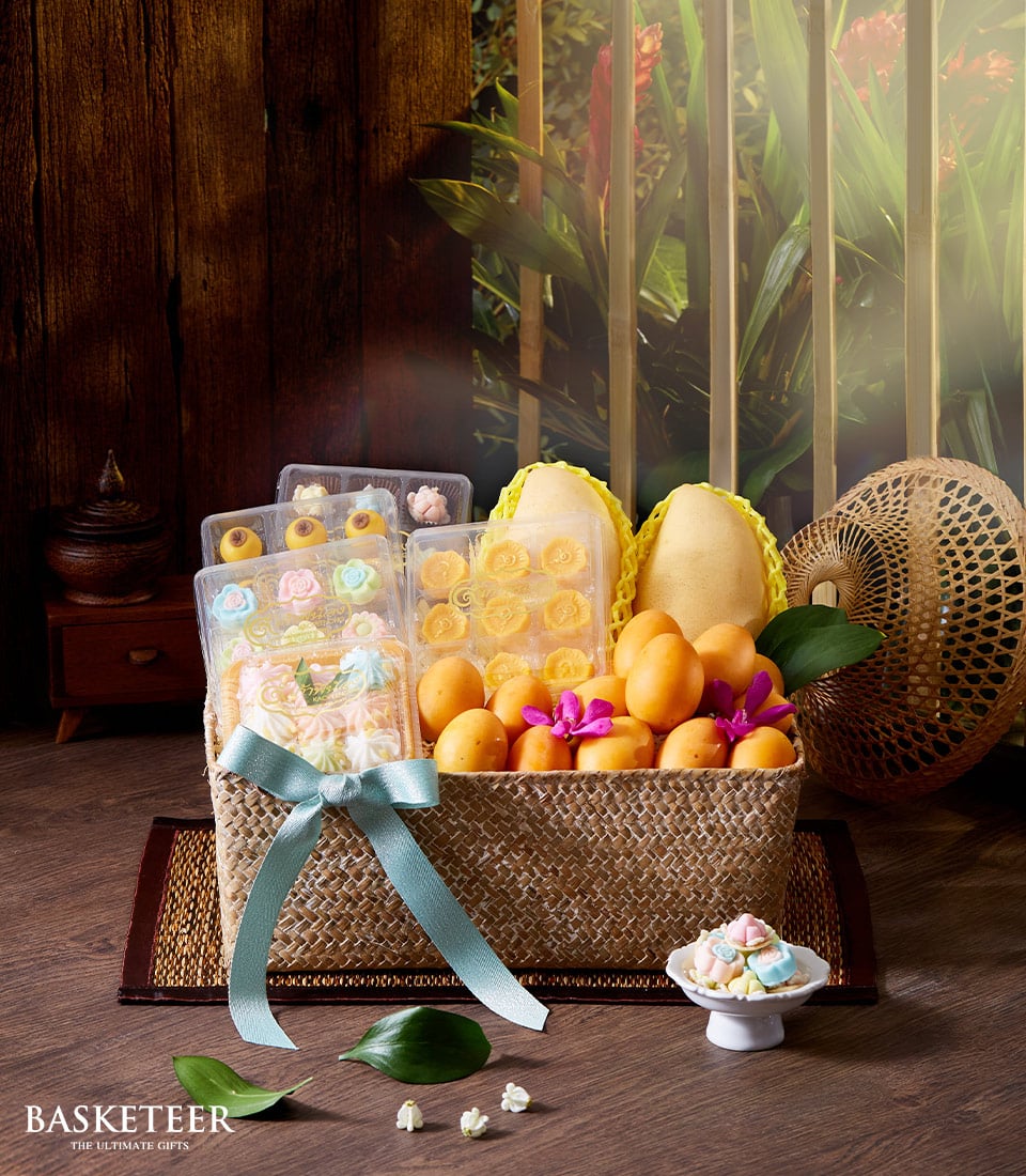 Yellow tropical fruits and Thai desserts in woven basket with orchids, Songkran gift