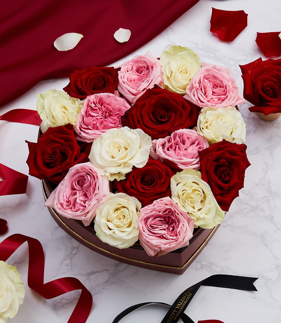 Red, pink and cream roses in luxury heart-shaped box with gold ribbon for Valentine's Day