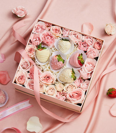 Luxury gift box with fresh pink roses, chocolate-covered strawberries, and pink satin ribbon for Valentine's Day
