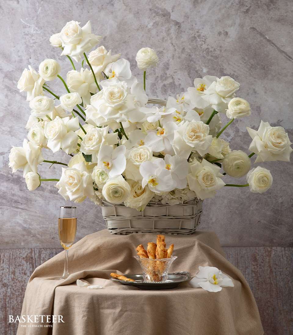 Timeless English white roses and orchids in light grey wicker basket, luxury floral arrangement
