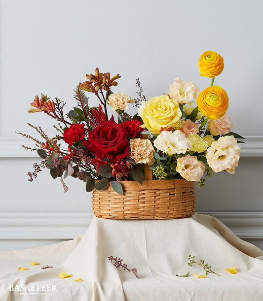 Sunset Glow Ecuadorian roses with yellow ranunculus and cream carnations in woven basket, get well gift