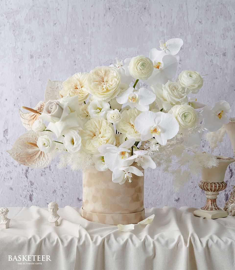 Luxurious white rose and orchid arrangement in beige velvet hatbox