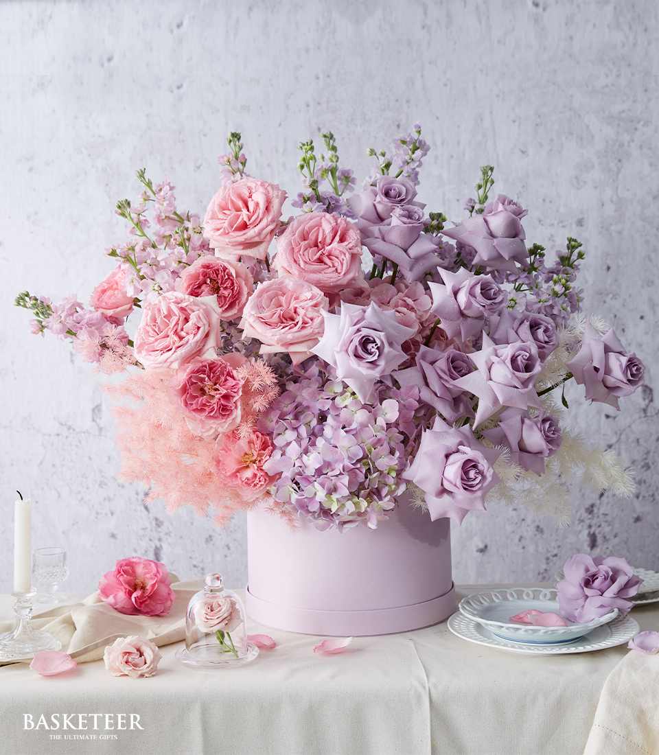 Luxe pink and purple rose collection in lavender hatbox with hydrangeas and feathered blooms