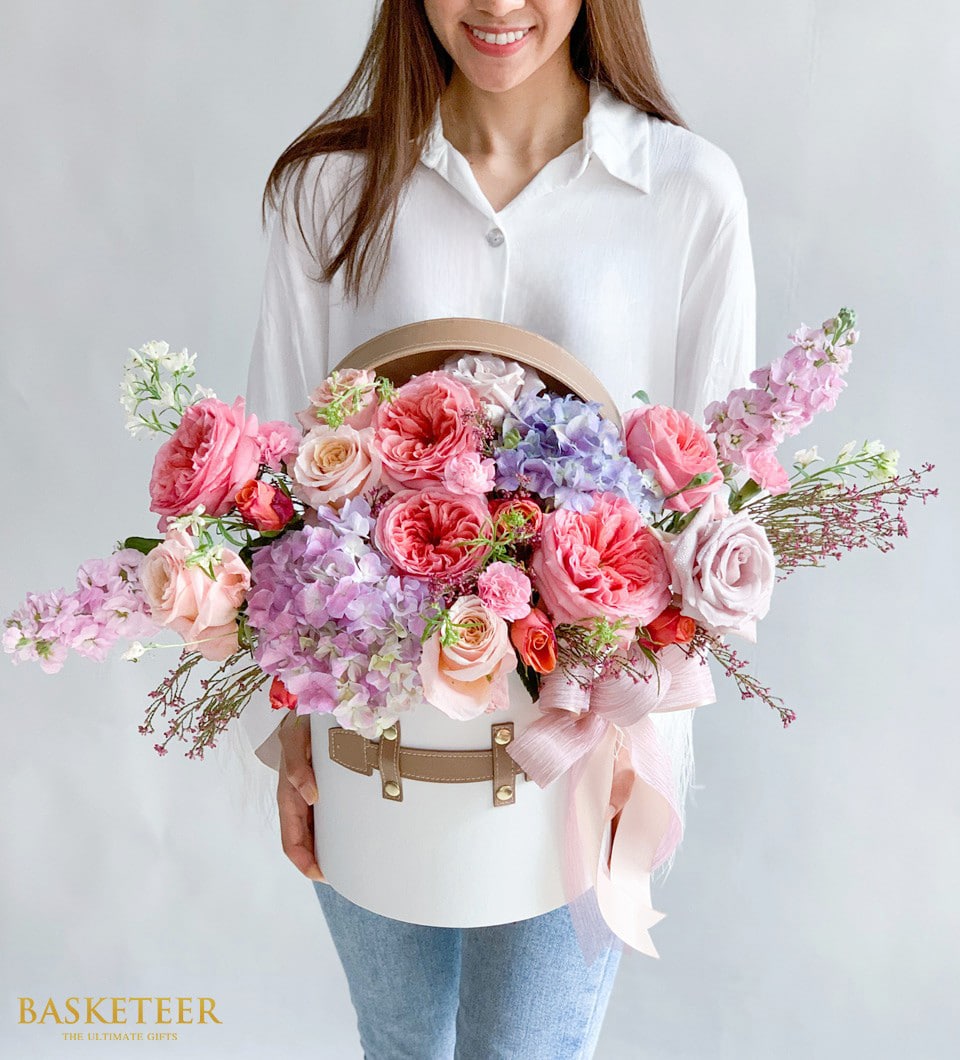Luxury flower box with pink roses, hydrangeas, and stock flowers in round white gift box with leather handle
