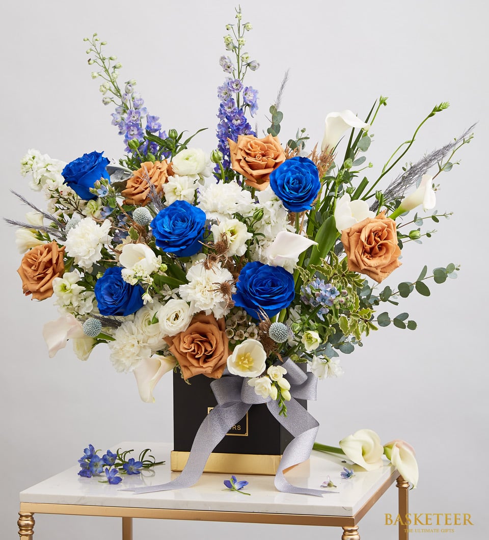 Vibrant blue and orange rose arrangement with white calla lilies in luxury black gift box, birthday flowers