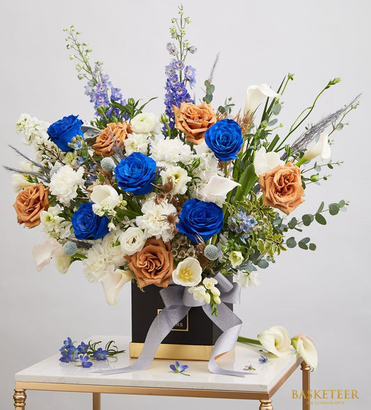 Vibrant blue and orange rose arrangement with white calla lilies in luxury black gift box, birthday flowers