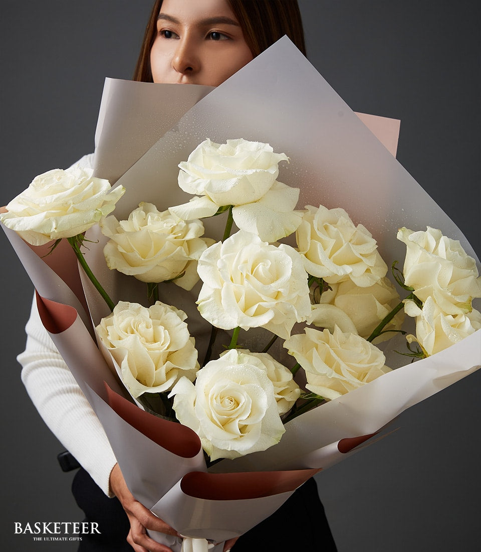 Fresh white roses with water droplets, wrapped in frosted paper for Valentine's Day gifting
