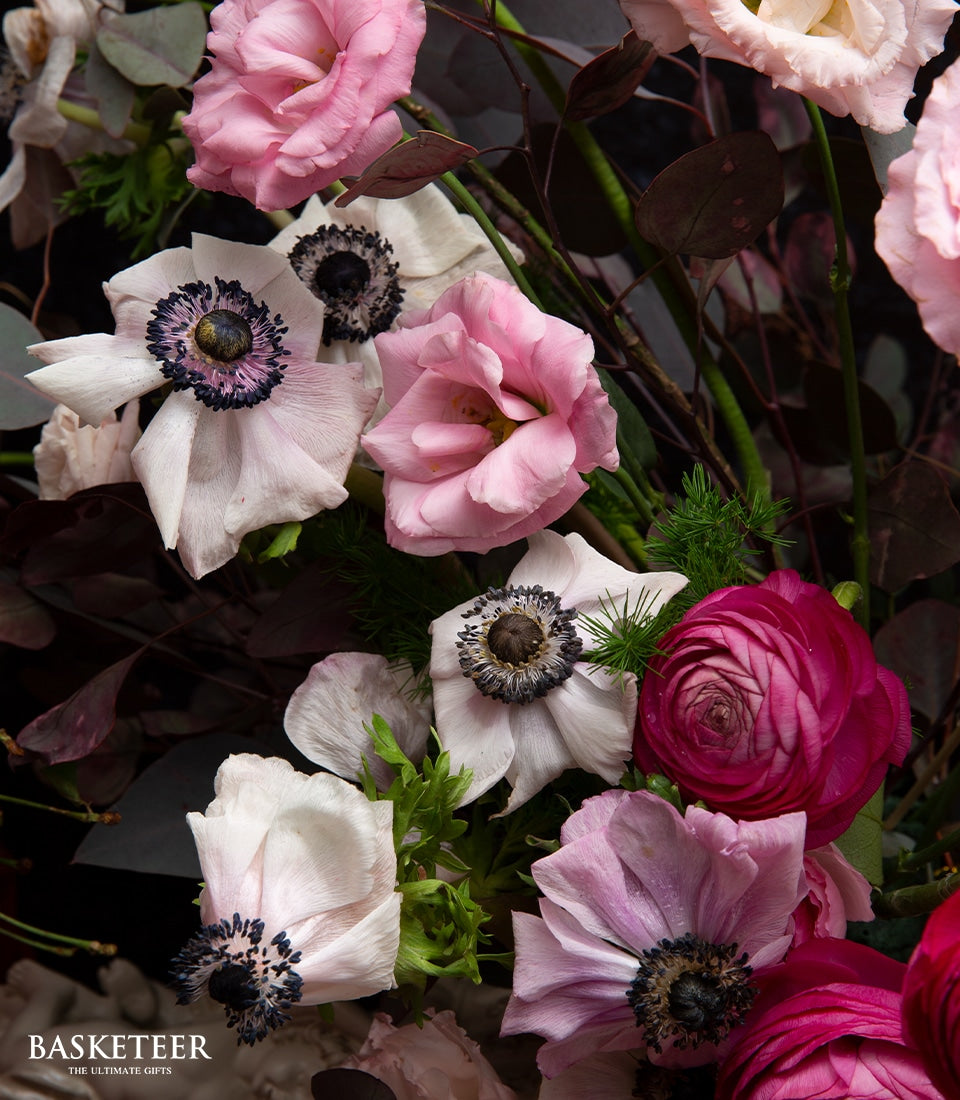 Elegant English-style floral arrangement with pink Eustoma, white Anemones, and deep fuchsia Ranunculus in dark green foliage