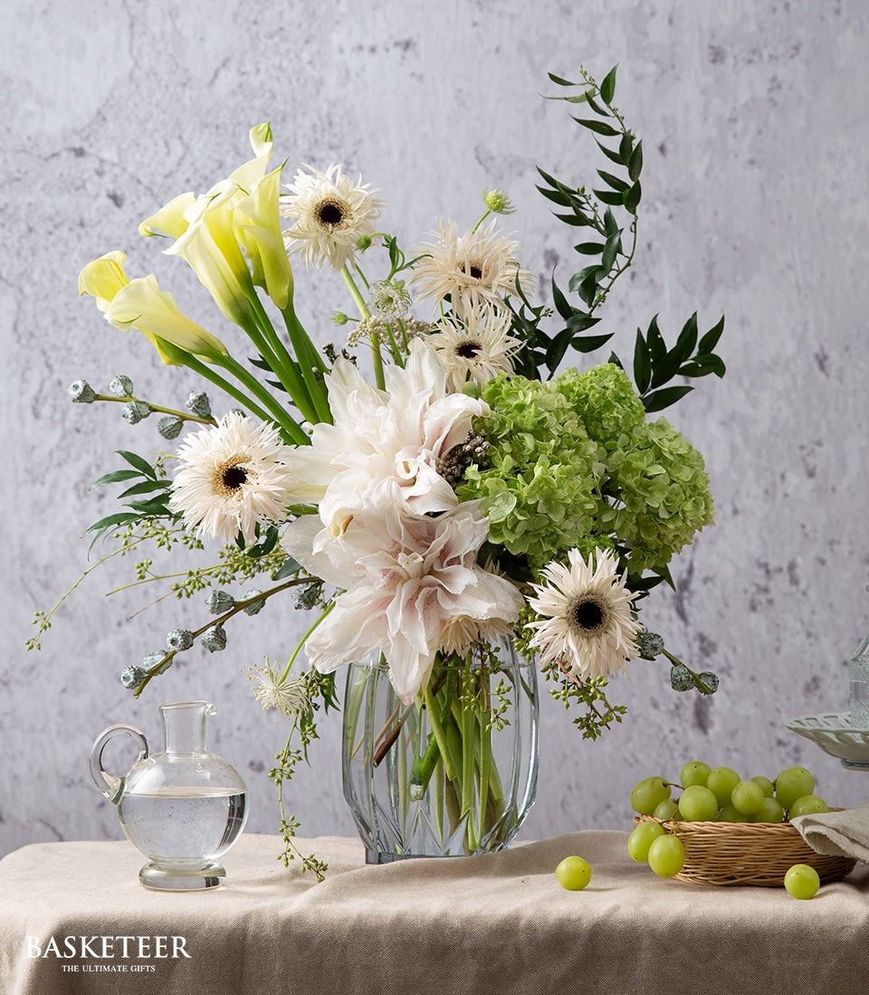 White and pink dahlia arrangement with yellow calla lilies and hydrangeas in glass vase, fresh fruit gift set