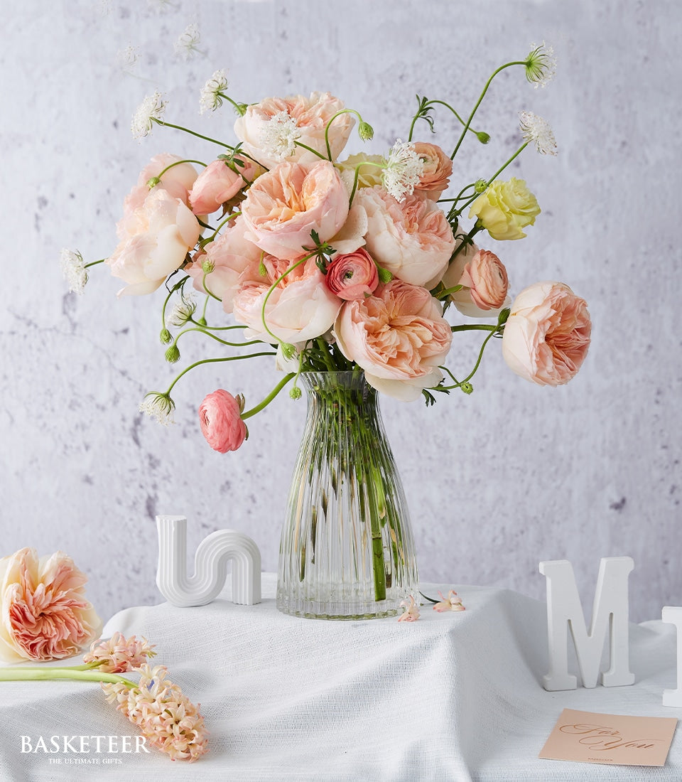 Light peach and pink roses with ranunculus in glass vase, fresh get well flowers
