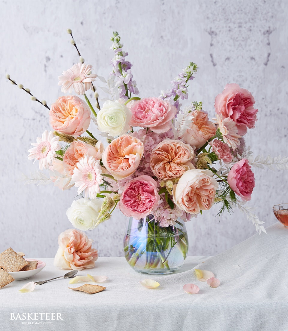 Pink and peach garden roses with ranunculus in clear glass vase, get well flowers arrangement