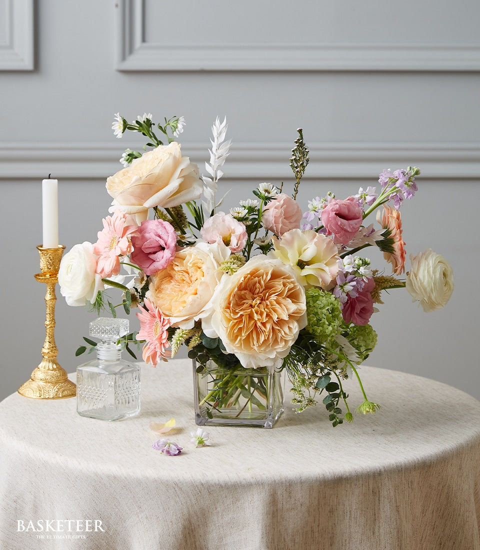 Pastel peach and pink roses with cream gerberas in clear glass vase, dining table centerpiece