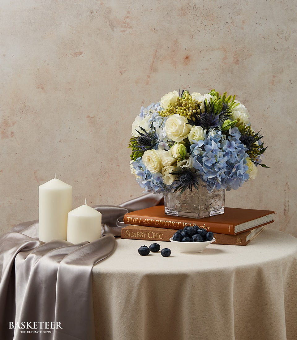 Blue and white hydrangea floral arrangement in glass cube vase for elegant dining table display