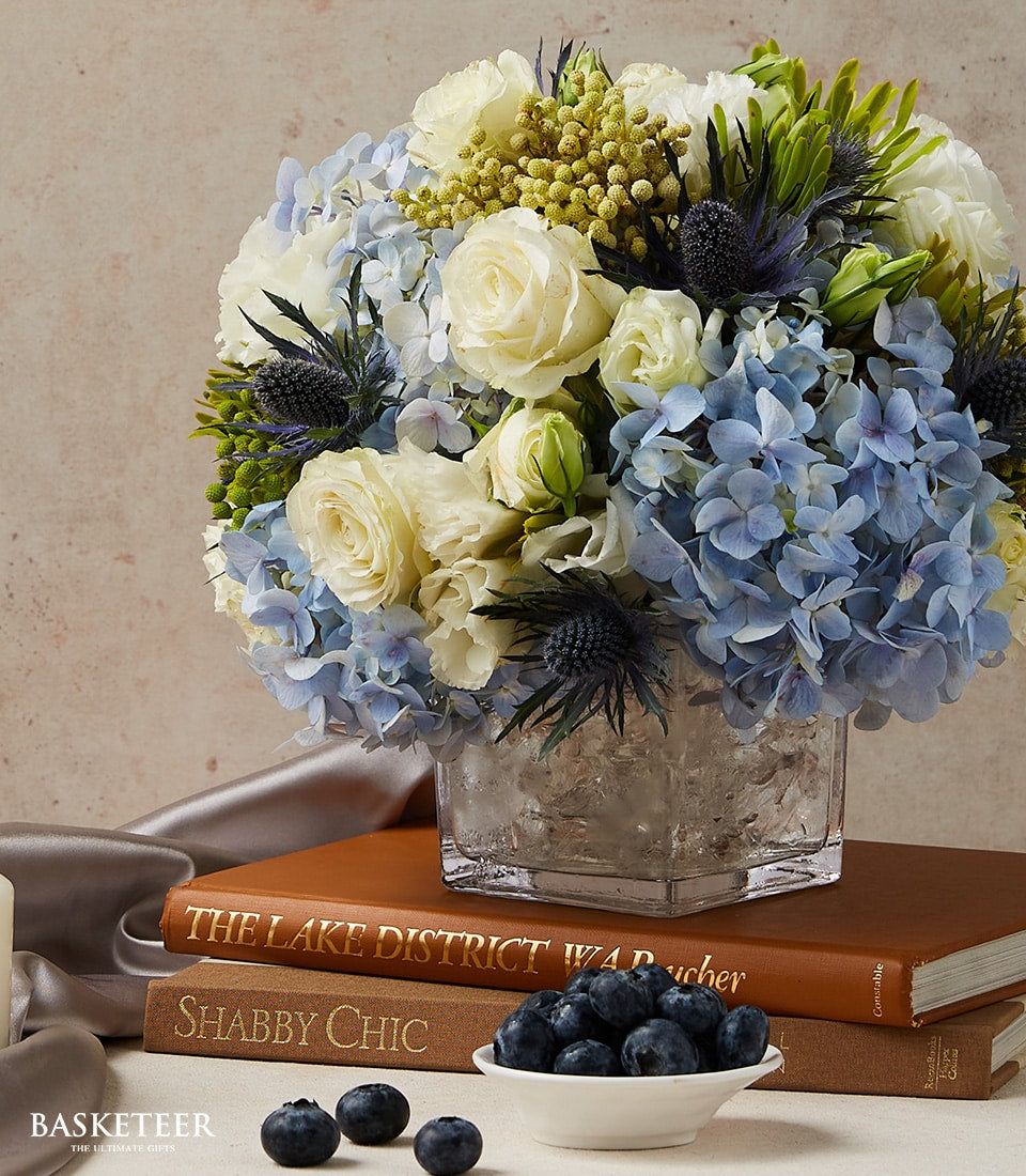 Elegant white roses and blue hydrangeas in glass vase, premium fresh flowers for gifting
