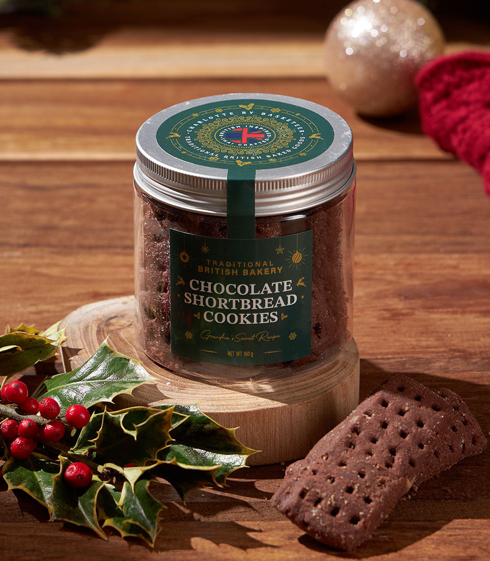 Classic chocolate shortbread cookies in glass jar with festive green label and holly sprig, Christmas gift hamper