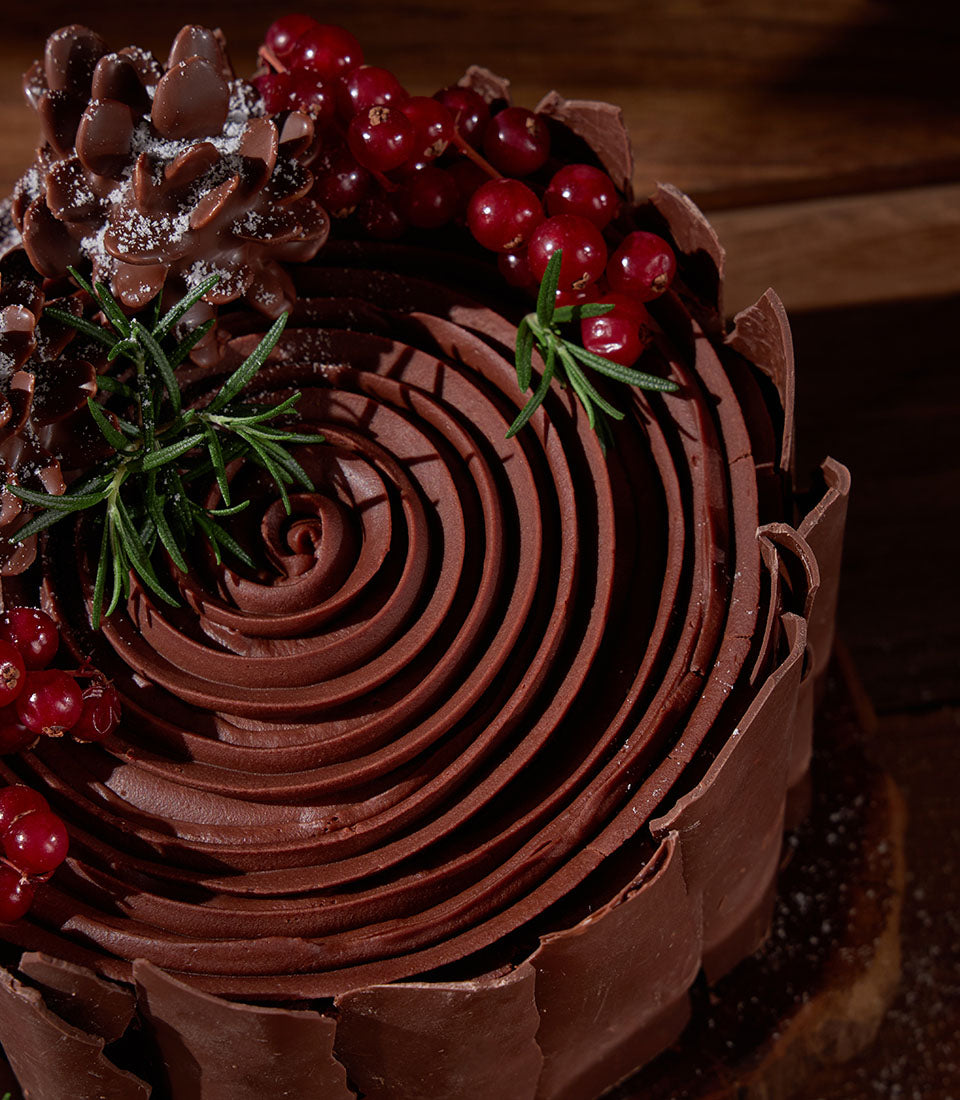 Charlotte Bakery artisan cake with rich chocolate ganache, decorated with fresh red currants and chocolate curls. Order a custom cake Bangkok today!