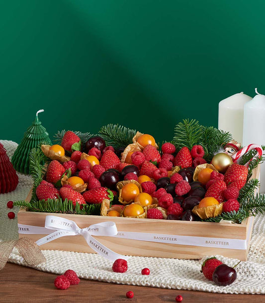 Wooden Christmas fruit gift box with strawberries, raspberries, cherries and physalis on white knit fabric