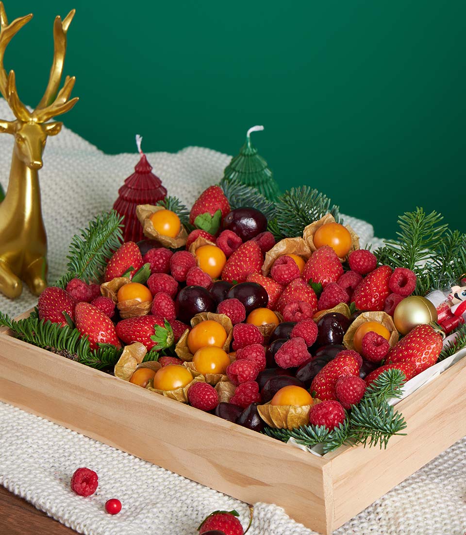 Festive berry fruit gift box with strawberries, raspberries, cherries, and physalis on wooden tray