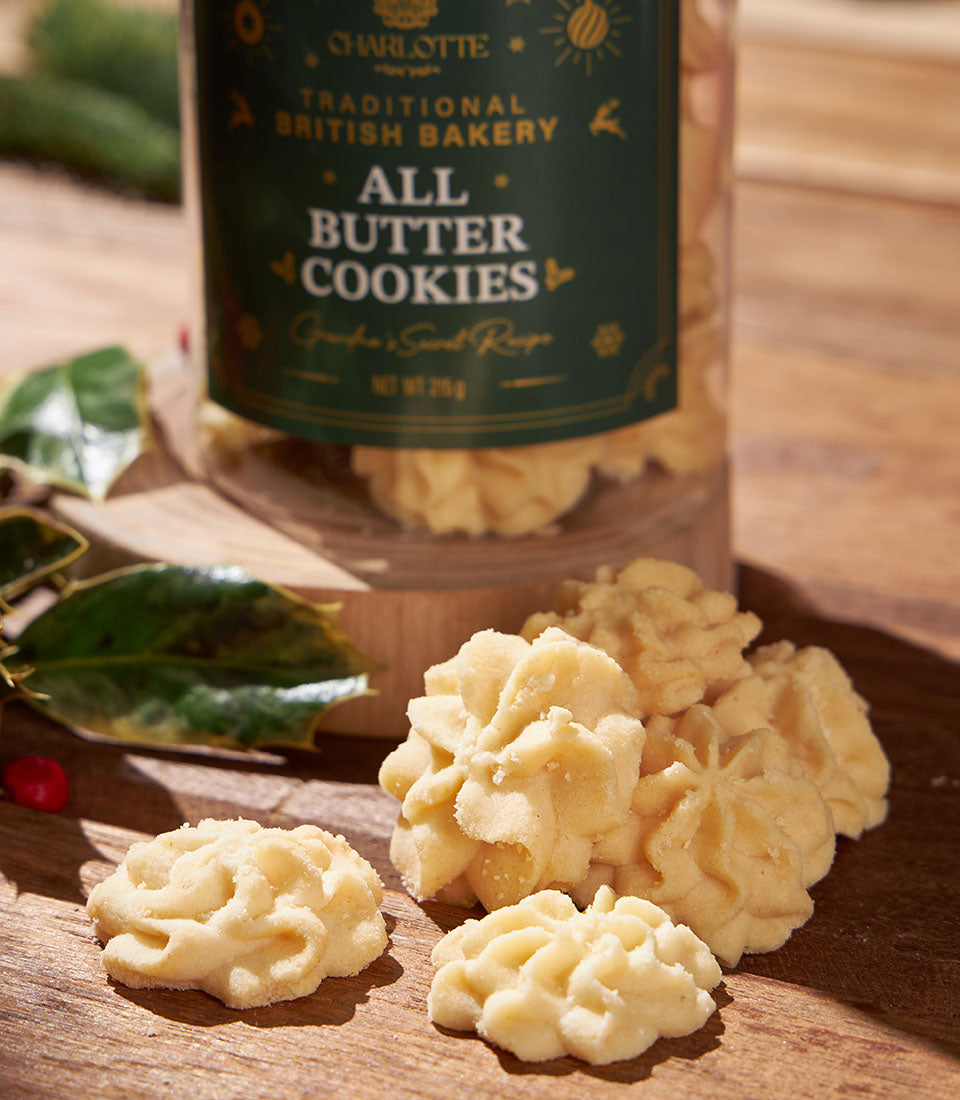 Charlotte Bakery's British cookies, a classic artisan treat. Butter cookies are piled on a wooden board, with a jar of them in the background. Perfect for a bakery gift in Thailand.