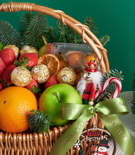 Festive wicker gift basket with fresh fruit, Ferrero Rocher chocolates, and Christmas ornaments