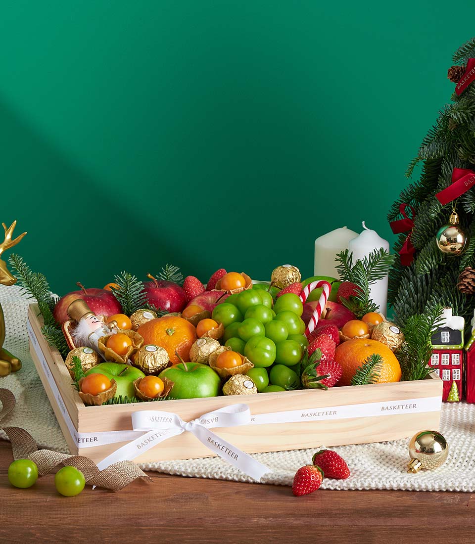 Luxury festive mixed fruit gift box with apples, grapes, strawberries, and gold chocolates, tied with white ribbon