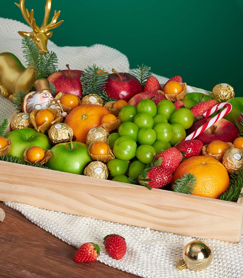 Luxury festive mixed fruit gift box with apples, grapes, strawberries and chocolates in wooden crate