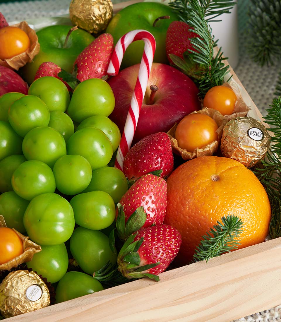Luxury festive mixed fruit gift box with grapes, strawberries, apples, oranges, physalis and chocolates in wooden crate