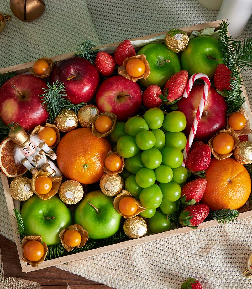 Luxury festive fruit gift box with fresh apples, oranges, strawberries, grapes, and goldenberries arranged on wooden tray