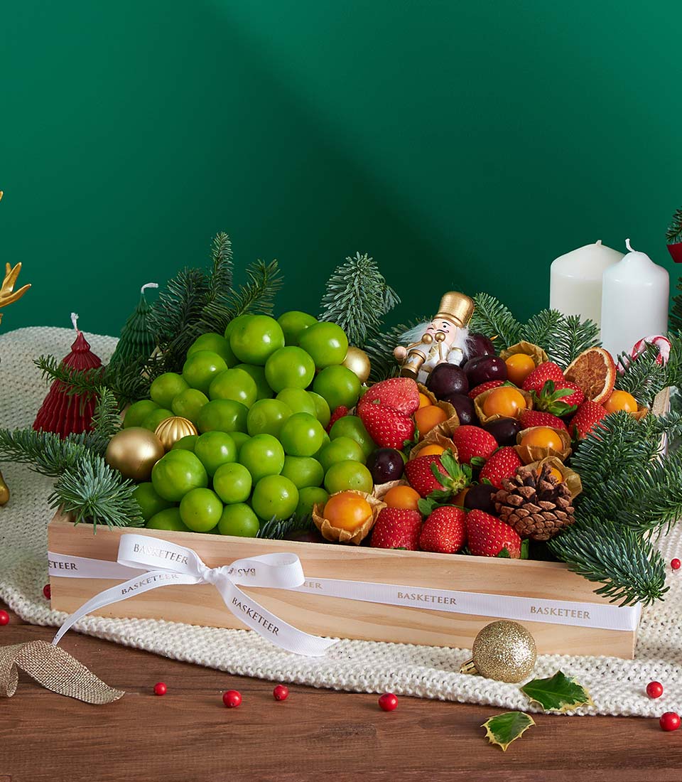 Premium festive fruit gift box with green plums, strawberries, cherries, and Shine Muscat grapes, gold ornaments and pine