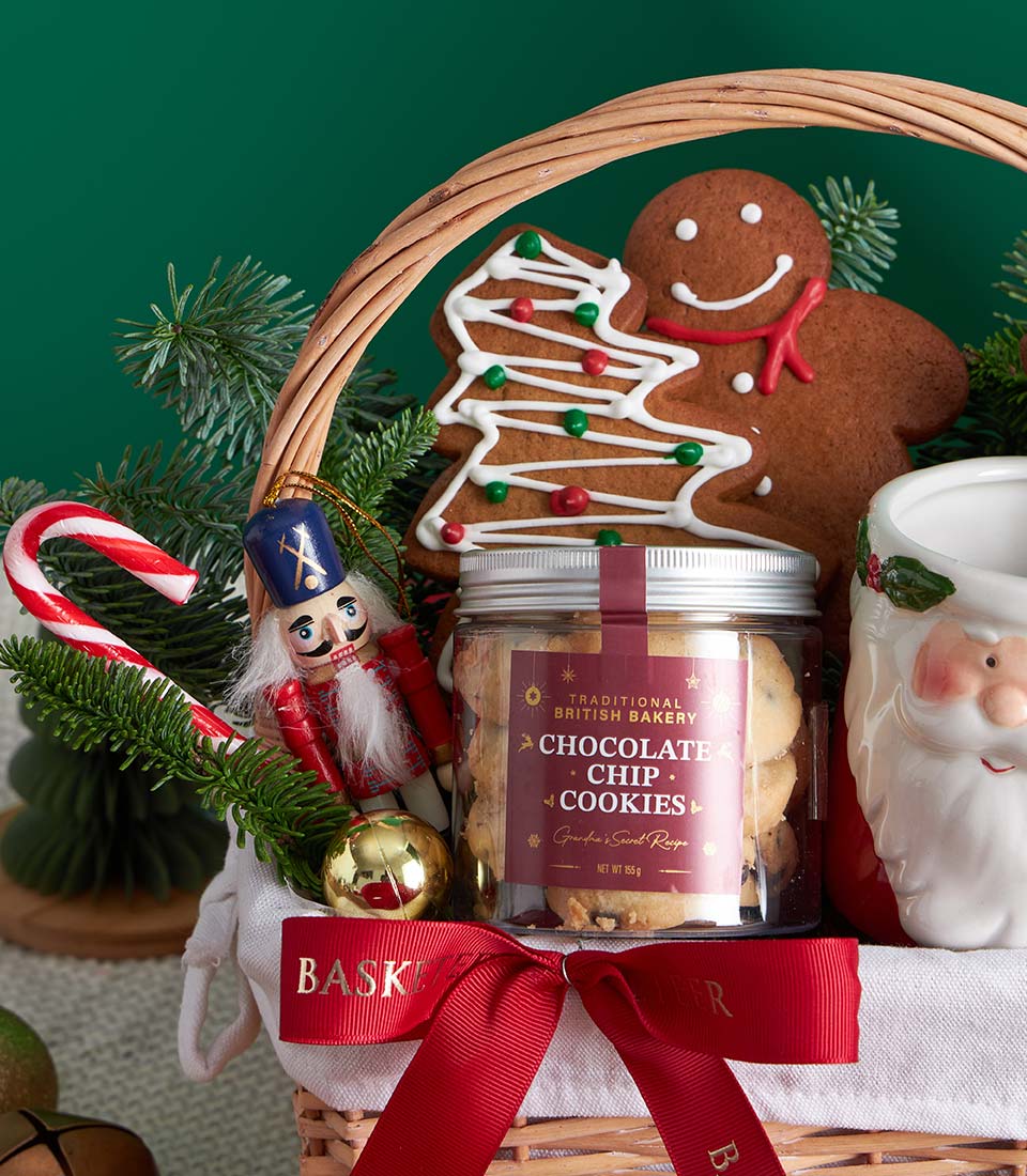 Festive Christmas gift basket with gingerbread cookies, chocolate chip biscuits, Santa mug, and holiday ornaments