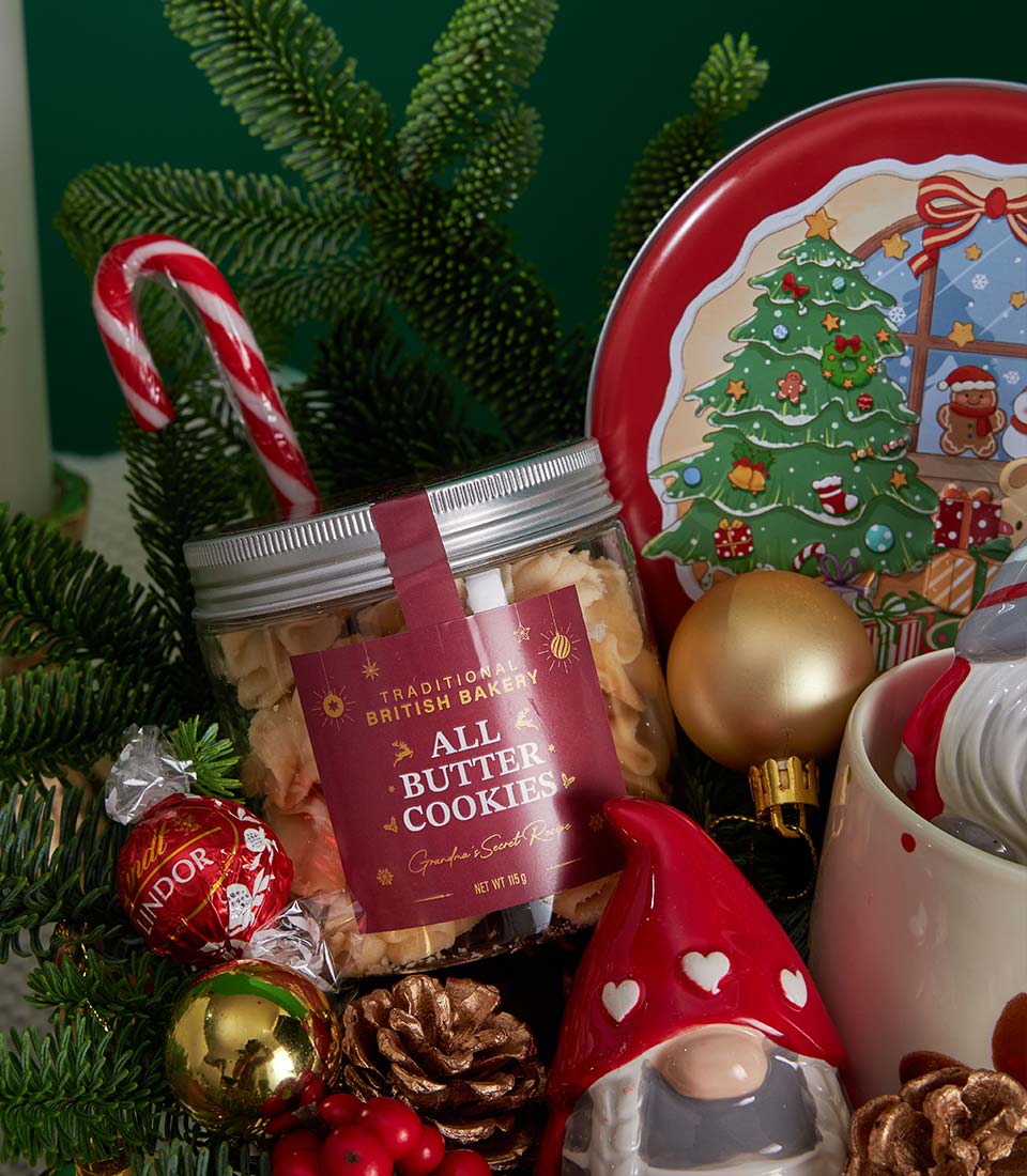 Premium Christmas gift basket with butter cookies, chocolate truffles, candy cane, and festive ornaments nestled in greenery