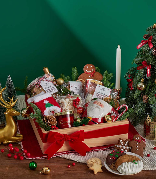 Festive Christmas gift basket with hot chocolate, macadamia cookies, Santa mug, red velvet ribbon and pine branches
