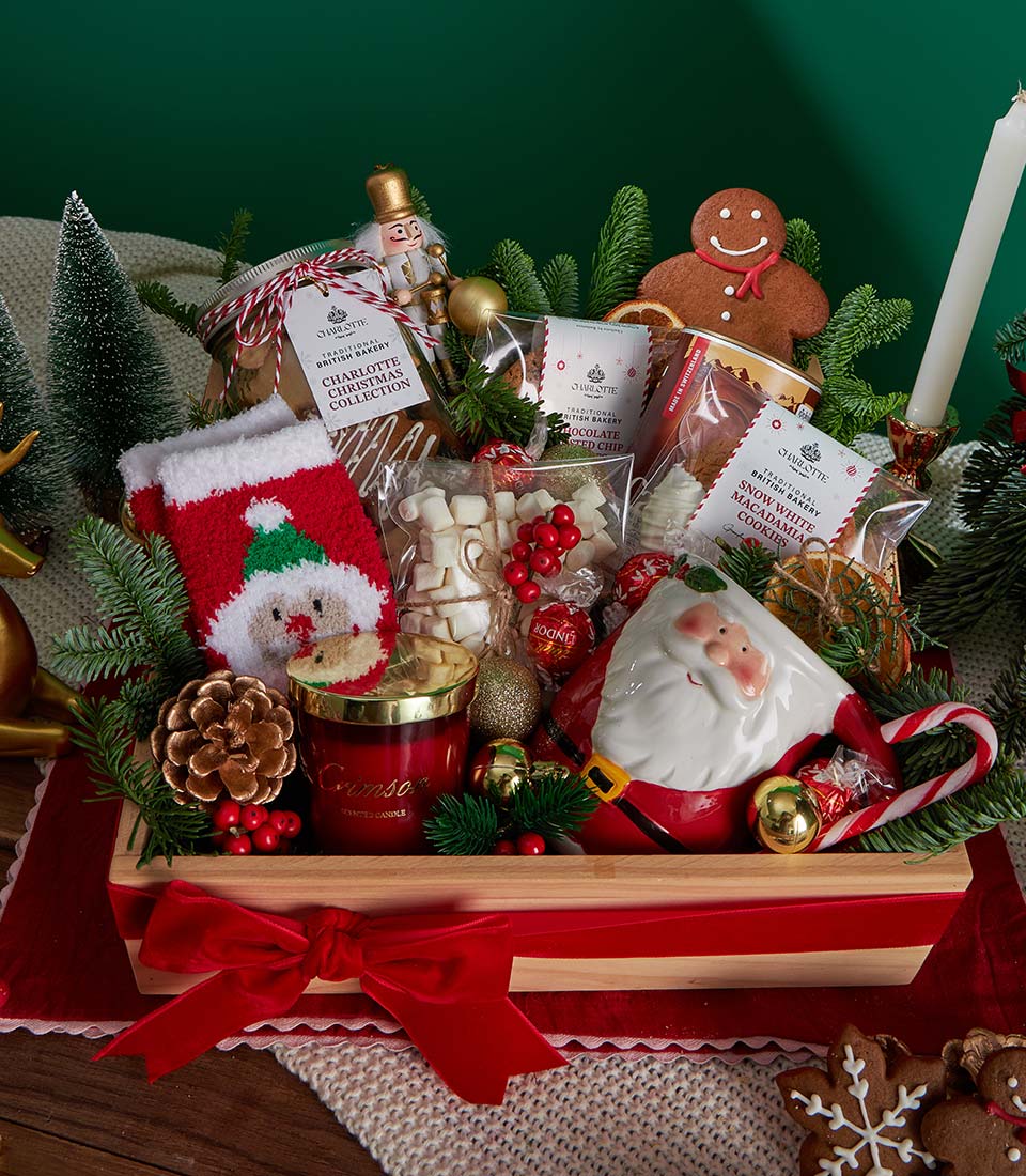 Festive Christmas gift basket with British cookies, hot chocolate, marshmallows, nutcracker, and festive trimmings in wooden