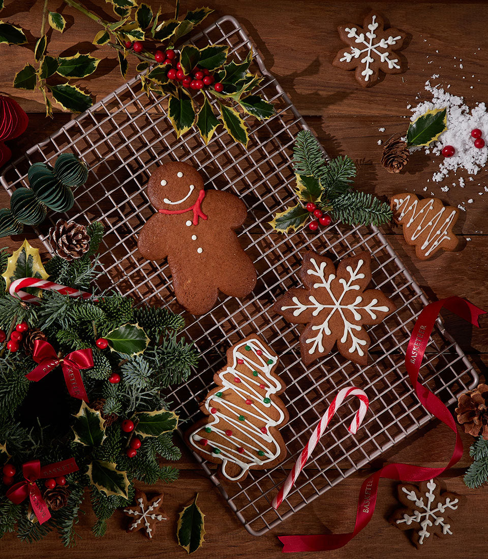 Artisan gingerbread cookies from Charlotte Bakery, including a gingerbread man and snowflake shapes, decorated with white icing and festive greenery.