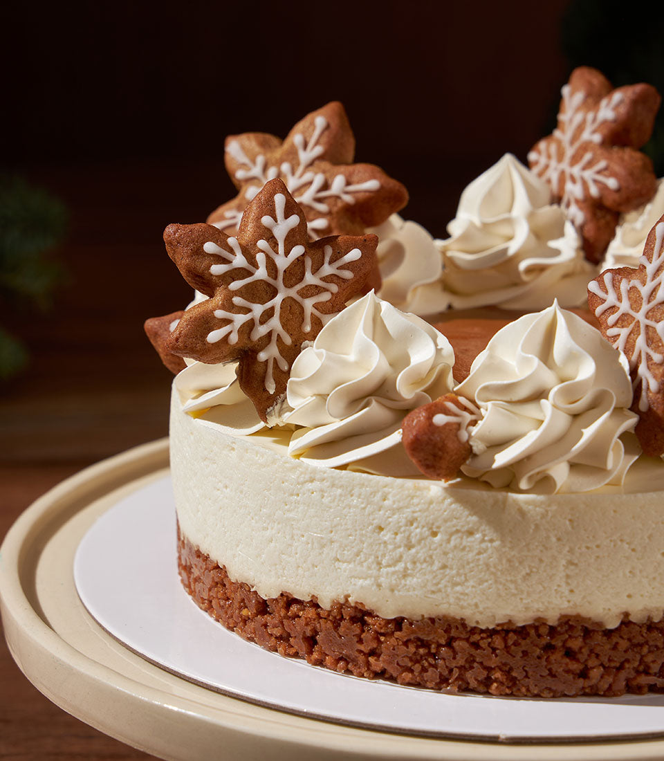 Charlotte Bakery artisan cheesecake with Biscoff crust, swirls of cream cheese frosting, and gingerbread snowflake cookies. Order a custom cake in Bangkok for Christmas!