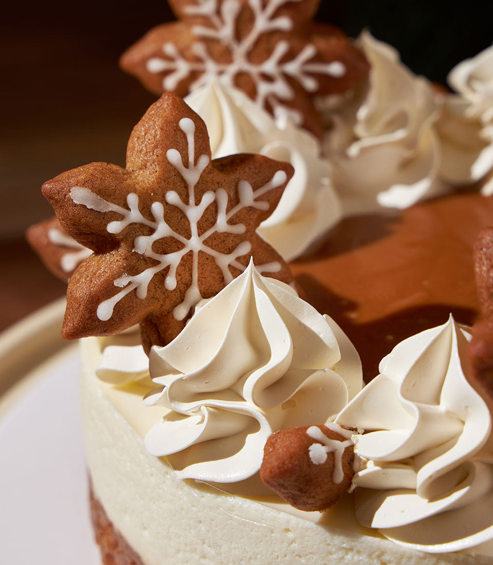 Charlotte Bakery Christmas cheesecake. Festive gingerbread snowflakes and delicate cream cheese frosting adorn this artisan cake. A perfect custom cake order for Bangkok delivery.