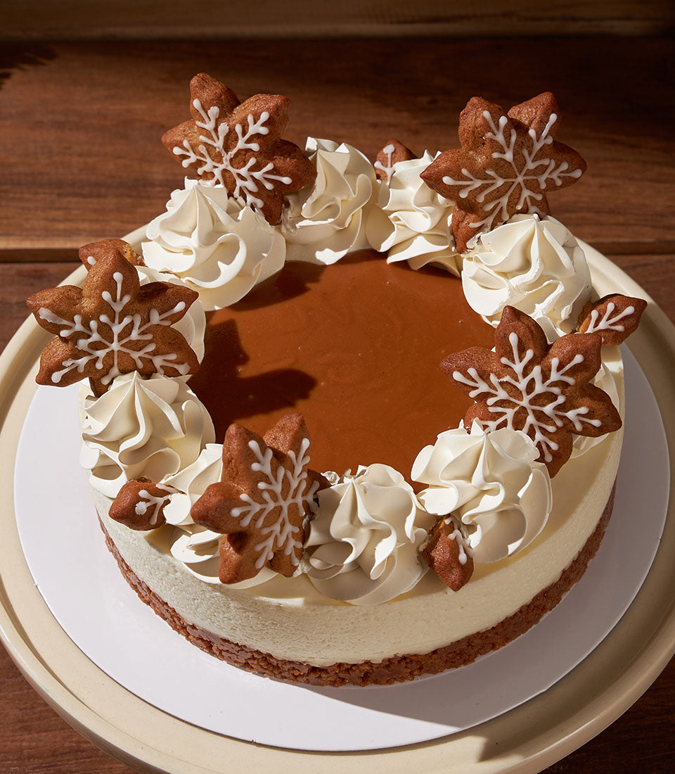 Charlotte Bakery artisan cheesecake with Biscoff topping, decorated with gingerbread snowflakes and cream cheese frosting. Order a custom cake in Bangkok!