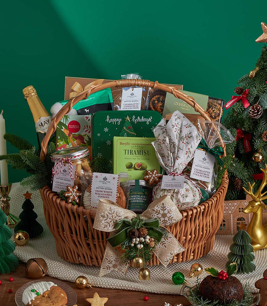 Luxury Christmas gourmet gift basket with sparkling wine, tiramisu, macadamia cookies, and festive ribbon in woven wicker