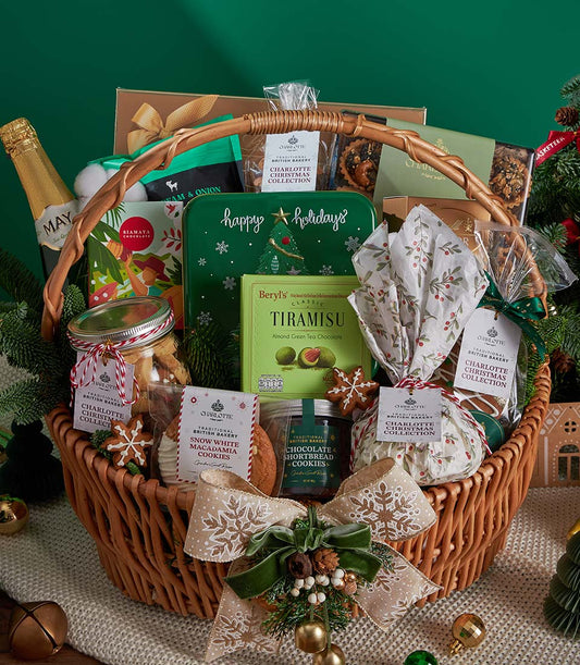 Woven wicker Christmas gift basket with sparkling wine, gourmet chocolates, British bakery treats, and festive ribbon bow