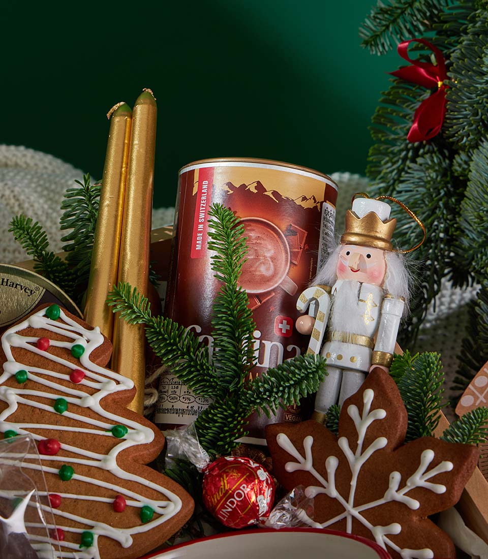 Festive Christmas gift box with Swiss hot chocolate, gingerbread cookies, golden candles, and chocolate truffles