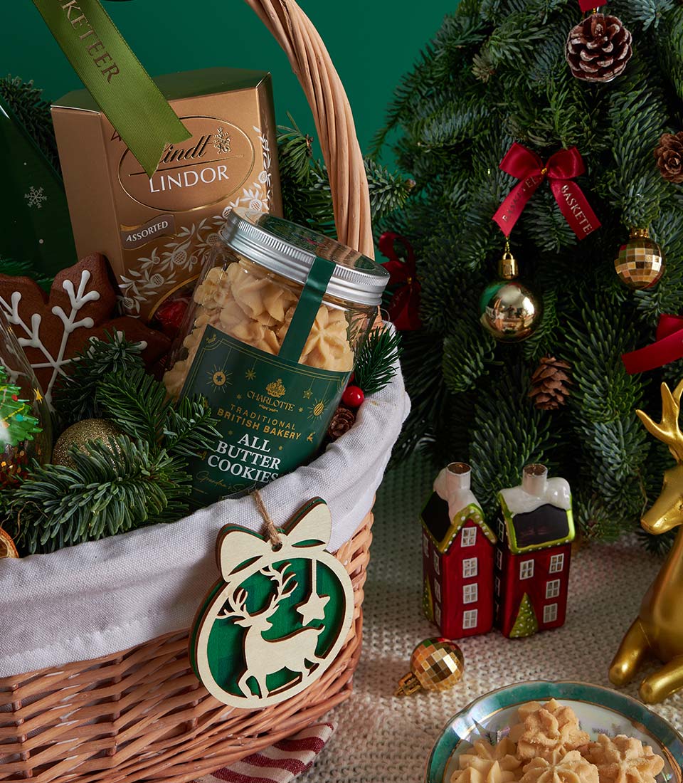 Wicker Christmas gift basket with Lindt chocolates, all-butter cookies, and wooden reindeer ornament