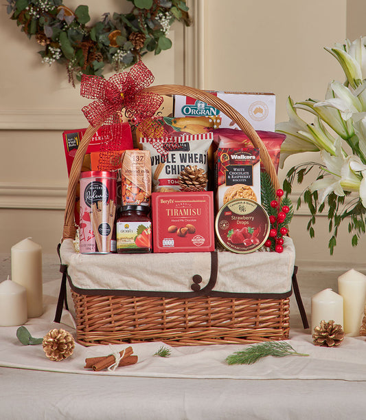 Woven wicker gift basket with red mesh bow filled with gourmet snacks, chocolates, and artisan treats for New Year