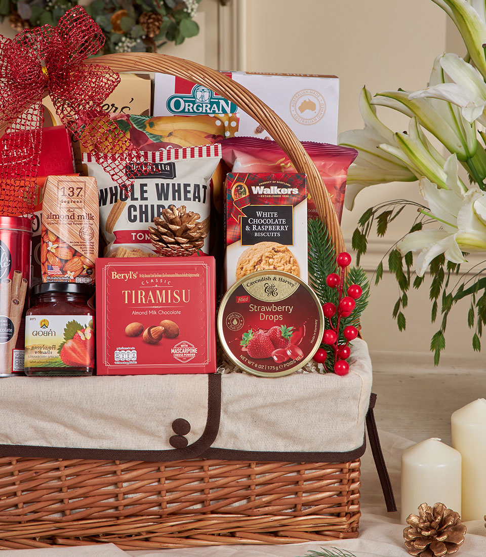Woven wicker gift basket with red bow filled with gourmet cookies, chocolates, and snacks for New Year gifting