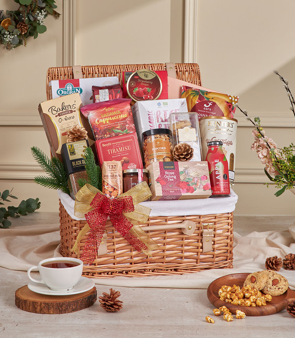 Luxury wicker hamper filled with gourmet coffee, tea, cookies, and artisan snacks, tied with gold and red ribbon for New