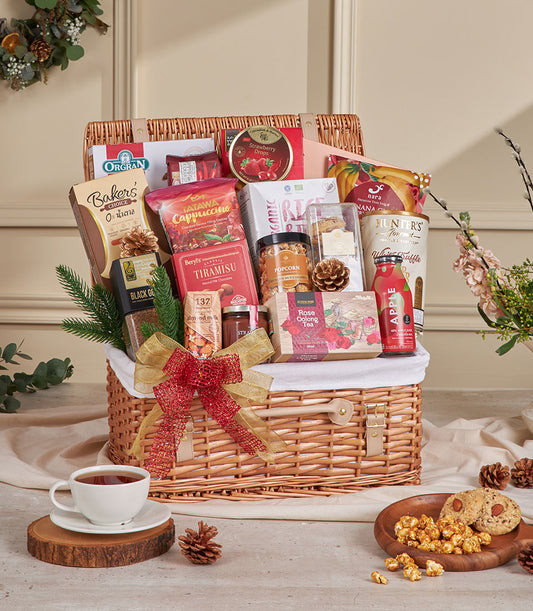 Luxury wicker hamper filled with gourmet coffee, tea, cookies, and artisan snacks, tied with gold and red ribbon for New