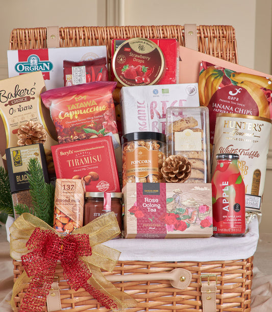 Woven wicker hamper with gourmet coffee, chocolates, cookies, and snacks tied with red gold ribbon for New Year gifting